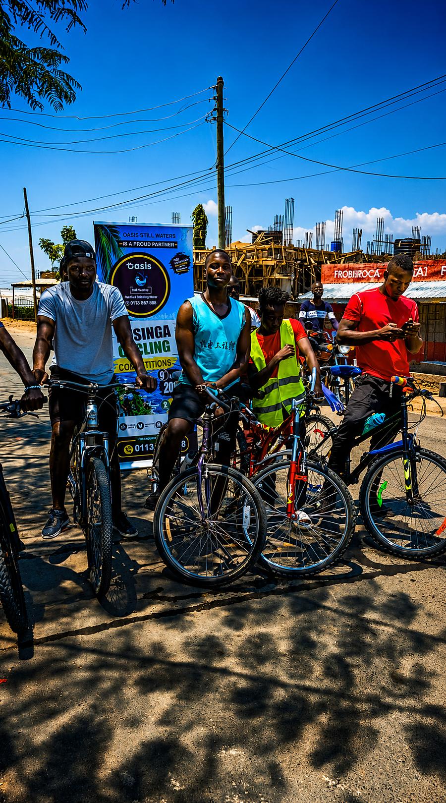 Cyclists posing with their bikes beside the Oasis Still Waters banner before the Rusinga Cycling Competition